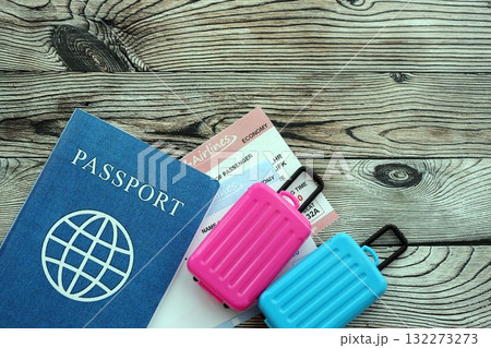 Passport with boarding pass tickets and toy luggage bags on wooden background close up 132273273