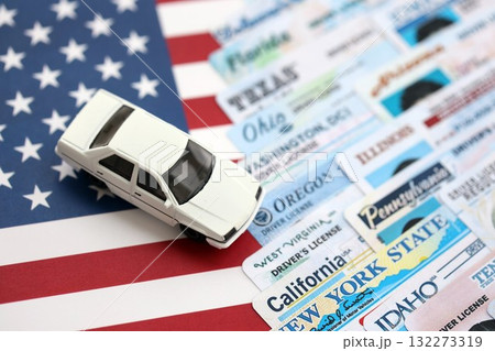 Toy car on big amount of driving licenses from different USA states on flag close up. Stack of driving license specimen cards 132273319