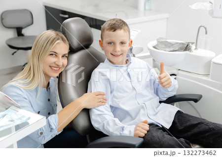 Friendly dentist comforting young boy sitting on dentist chair Friendly dentist comforting young boy sitting on dentist chair 132273462