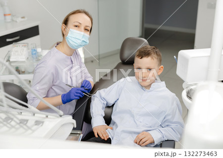 Happy dentist and child patient showing thumbs up in dental clinic 132273463