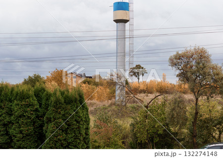Rural Landscape with Tall Silver Water Tower, Blue Top, Autumn Trees, Overcast Sky, and Green Foliage Scenic Countryside View Rural Landscape with Tall Silver Water Tower, Blue Top, Autumn Trees, Overcast Sky, and Green Foliage Scenic Countryside View 132274148