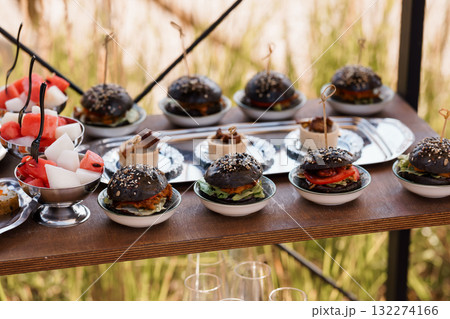 Gourmet Black Burger Skewers Catering Presentation. Delicious Mini Food, Outdoor Event, Silver Platters, Red Watermelon, Rustic Wood Table, Appetizers Gourmet Black Burger Skewers Catering Presentation. Delicious Mini Food, Outdoor Event, Silver Platters, Red Watermelon, Rustic Wood Table, Appetizers 132274166