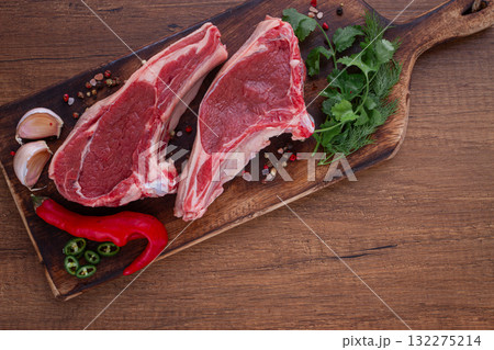 Freshly sliced lamb chops, with herbs and vegetables, on a wooden board, ready to cook, on a wooden table, Freshly sliced lamb chops, with herbs and vegetables, on a wooden board, ready to cook, on a wooden table, 132275214