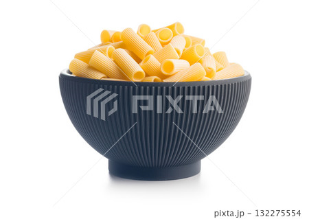 Uncooked rigatoni pasta in bowl isolated on white background. Uncooked rigatoni pasta in bowl isolated on white background. 132275554