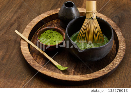Traditional Matcha Preparation. High-angle view of matcha tea being prepared with a bamboo whisk Traditional Matcha Preparation. High-angle view of matcha tea being prepared with a bamboo whisk 132276018
