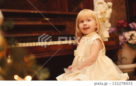 Portrait happy smiling little girl child playing on piano at home near christmas tree 132276033