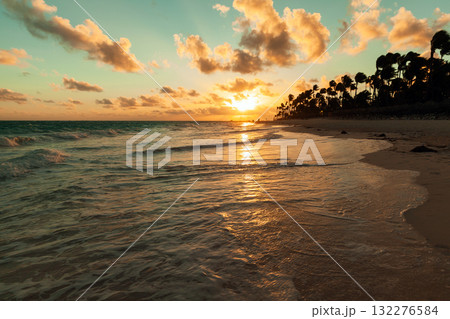 A serene sunset paints the ocean and sandy shore with warm gold tones. A serene sunset paints the ocean and sandy shore with warm gold tones. 132276584