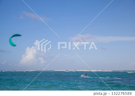 A lone kite surfer glides across turquoise waves as a teal kite soars 132276589