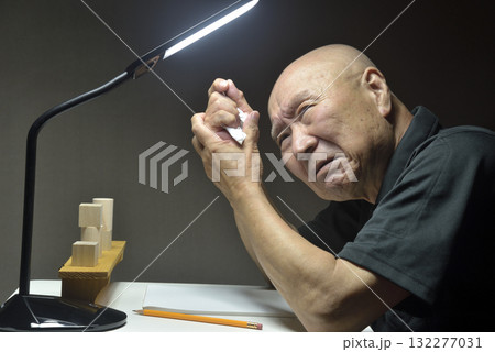 机の前で悔しがる老人 132277031