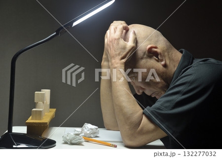 机の前で悔しがる老人 132277032