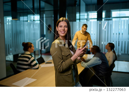Confident business woman smiling while using smartphone during a team meeting in a modern office environment. Concept of communication, leadership, and professional confidence. Confident business woman smiling while using smartphone during a team meeting in a modern office environment. Concept of communication, leadership, and professional confidence. 132277063