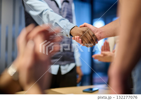 Two businessmen shaking hands after successful negotiation in a modern office, symbolizing partnership, agreement, success, and teamwork. A woman in the background applauds the deal. Two businessmen shaking hands after successful negotiation in a modern office, symbolizing partnership, agreement, success, and teamwork. A woman in the background applauds the deal. 132277076