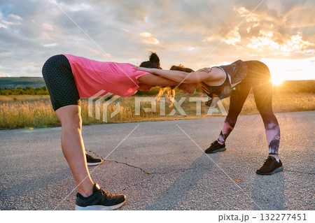 Two Women Athletes Stretching at Sunset in Beautiful Natural Surroundings Two Women Athletes Stretching at Sunset in Beautiful Natural Surroundings 132277451
