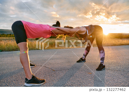 Two Women Athletes Stretching at Sunset in Beautiful Natural Surroundings Two Women Athletes Stretching at Sunset in Beautiful Natural Surroundings 132277462