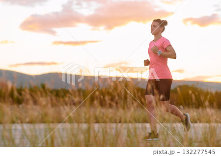Determined Athlete Running in the Sun amidst Beautiful Nature 132277545
