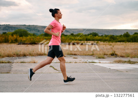 Determined Athlete Running in the Sun amidst Beautiful Nature 132277561