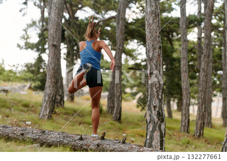 Fearless Woman Conquering Wooden Obstacles in the Dangerous Forest Terrain. Fearless Woman Conquering Wooden Obstacles in the Dangerous Forest Terrain. 132277661