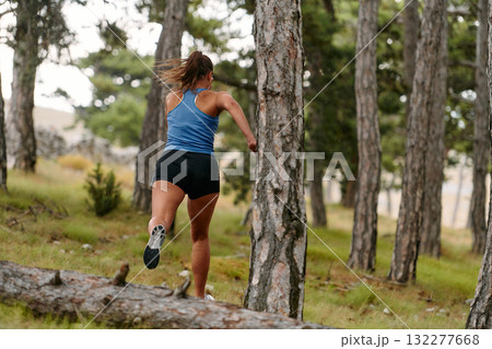 Fearless Woman Conquering Wooden Obstacles in the Dangerous Forest Terrain. 132277668