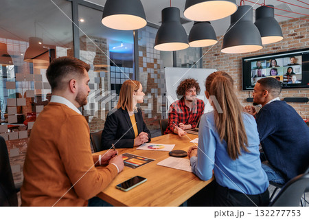 In the vibrant ambiance of a modern startup office, a diverse team of business professionals engage in discussions on various projects and develop new business strategies, epitomizing creativity and 132277753