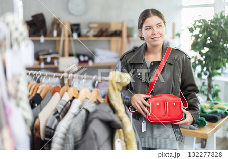 Positive young girl choosing handbag in clothing store Positive young girl choosing handbag in clothing store 132277828