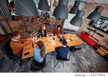Top view of a modern startup office, a diverse team of business professionals engage in discussions on various projects and develop new business strategies, epitomizing creativity and innovation in Top view of a modern startup office, a diverse team of business professionals engage in discussions on various projects and develop new business strategies, epitomizing creativity and innovation in 132277843