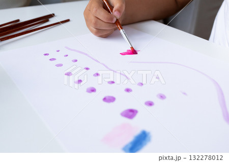 Child painting with watercolors on white paper at home 132278012