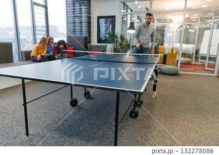 Business colleagues take a break from work to enjoy a game of table tennis, fostering teamwork and camaraderie in the workplace Business colleagues take a break from work to enjoy a game of table tennis, fostering teamwork and camaraderie in the workplace 132278086