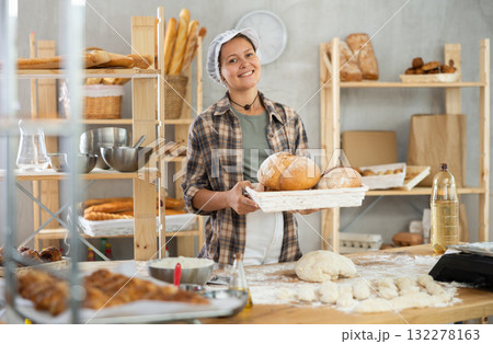 Bakery woman employee holds ready made bread of bread Bakery woman employee holds ready made bread of bread 132278163
