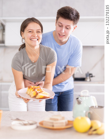 Cheerful young couple preparing table for tea-time in home kitchen 132278185