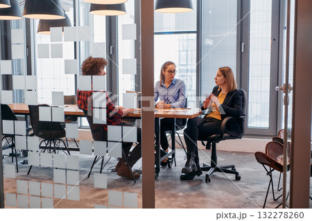 In the dynamic hustle and bustle of a business environment, a group of young business professionals walk down the corridor next to their office, while their colleagues collaborate inside, symbolizing In the dynamic hustle and bustle of a business environment, a group of young business professionals walk down the corridor next to their office, while their colleagues collaborate inside, symbolizing 132278260