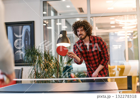 Business colleagues take a break from work to enjoy a game of table tennis, fostering teamwork and camaraderie in the workplace 132278318