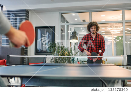 Business colleagues take a break from work to enjoy a game of table tennis, fostering teamwork and camaraderie in the workplace 132278360