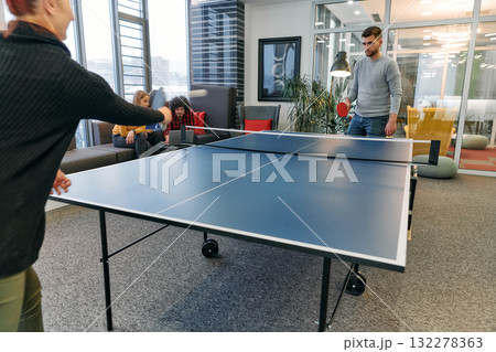Business colleagues take a break from work to enjoy a game of table tennis, fostering teamwork and camaraderie in the workplace Business colleagues take a break from work to enjoy a game of table tennis, fostering teamwork and camaraderie in the workplace 132278363
