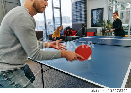 Business colleagues take a break from work to enjoy a game of table tennis, fostering teamwork and camaraderie in the workplace 132278392