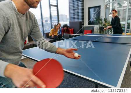 Business colleagues take a break from work to enjoy a game of table tennis, fostering teamwork and camaraderie in the workplace 132278584
