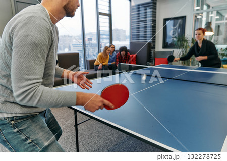 Business colleagues take a break from work to enjoy a game of table tennis, fostering teamwork and camaraderie in the workplace 132278725