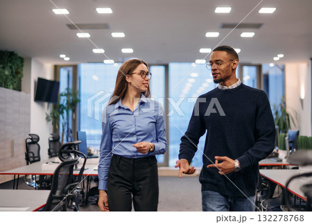 Dynamic Business Collaboration: Blonde Businesswoman and African American Colleague in Modern Office Setting. 132278768
