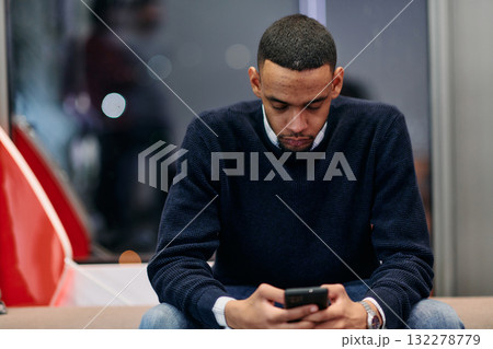 Young African American work in coworking space using smartphone analyzing online market trends, focused man worker reading financial news or browsing internet on phone. Technology concept 132278779