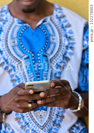 African American Teenager in Traditional Sudanese Attire Engaged with Smartphone African American Teenager in Traditional Sudanese Attire Engaged with Smartphone 132278803
