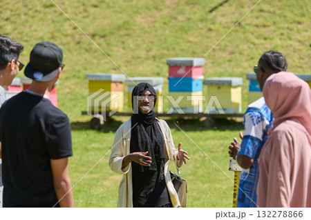 A diverse group of young friends and entrepreneurs explore small honey production businesses in the natural setting of the countryside. A diverse group of young friends and entrepreneurs explore small honey production businesses in the natural setting of the countryside. 132278866