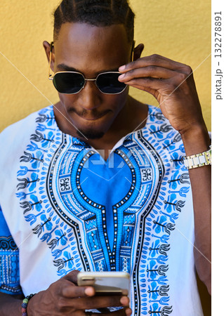 African American Teenager in Traditional Sudanese Attire Engaged with Smartphone 132278891