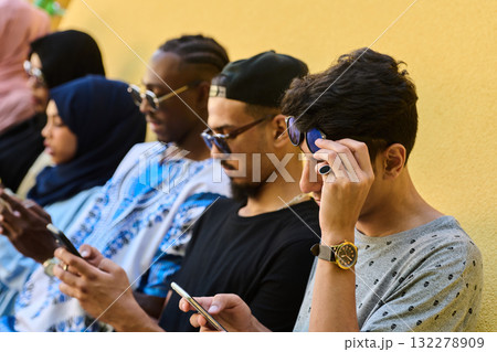 Diverse Teen Group Standing Together Against Wall Using Smartphones Diverse Teen Group Standing Together Against Wall Using Smartphones 132278909
