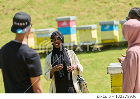 A diverse group of young friends and entrepreneurs explore small honey production businesses in the natural setting of the countryside. 132278936