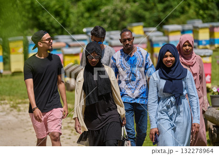 A diverse group of young friends and entrepreneurs explore small honey production businesses in the natural setting of the countryside. 132278964