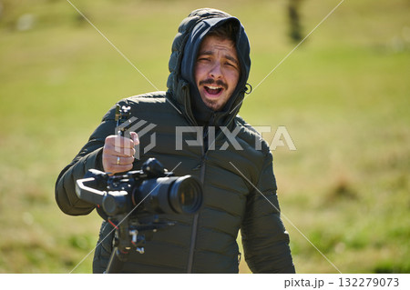 A skilled videographer, equipped with professional gear, captures the essence of nature's beauty, expertly documenting the scenic landscape in a cinematic masterpiece that reflects the seamless blend A skilled videographer, equipped with professional gear, captures the essence of nature's beauty, expertly documenting the scenic landscape in a cinematic masterpiece that reflects the seamless blend 132279073