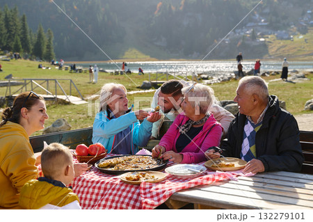 A family on a mountain vacation indulges in the pleasures of a healthy life, savoring traditional pie while surrounded by the breathtaking beauty of nature, fostering family bonds and embracing the A family on a mountain vacation indulges in the pleasures of a healthy life, savoring traditional pie while surrounded by the breathtaking beauty of nature, fostering family bonds and embracing the 132279101