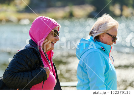 Senior friends enjoys a leisurely stroll in nature, immersed in joyous conversation, surrounded by the serenity of the outdoors, and creating timeless memories of companionship amidst the scenic Senior friends enjoys a leisurely stroll in nature, immersed in joyous conversation, surrounded by the serenity of the outdoors, and creating timeless memories of companionship amidst the scenic 132279133