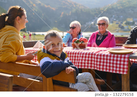 A family on a mountain vacation indulges in the pleasures of a healthy life, savoring traditional pie while surrounded by the breathtaking beauty of nature, fostering family bonds and embracing the 132279158