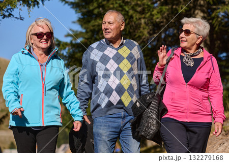 A family shares delightful moments with their friends amid the stunning landscapes of mountains, lakes, and winding paths, promoting a healthy lifestyle and the joy of familial bonds in the embrace of 132279168