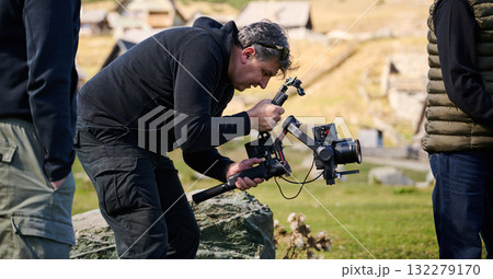 A skilled videographer, equipped with professional gear, captures the essence of nature's beauty, expertly documenting the scenic landscape in a cinematic masterpiece that reflects the seamless blend 132279170